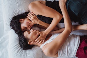 A loving couple lying in bed, embracing in an intimate, serene moment together.