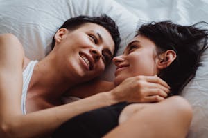 A loving couple sharing a tender moment in bed, embracing and smiling at each other.